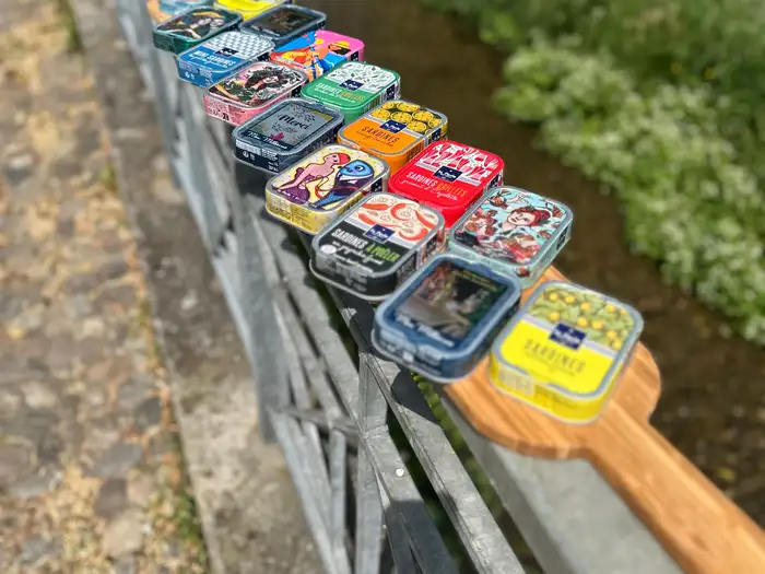 Bunte Sardinendosen in einer Reihe auf einem Brückengeländer